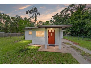 Charming single-story home featuring a red door, stucco siding, and a well-maintained front lawn at 2602 Ne 2Nd Ave, Ocala, FL 34470