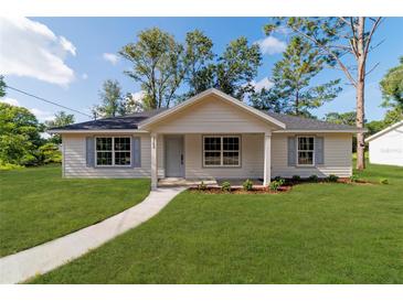 Charming single-story home with a well-manicured lawn, light blue shutters, and a welcoming front porch at 5388 Nw 9Th St, Ocala, FL 34482