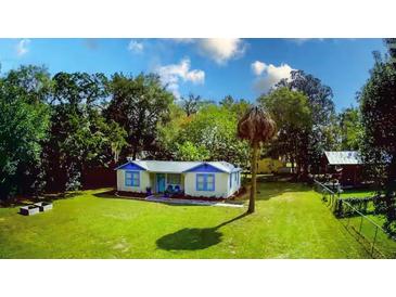 Charming cottage-style home with blue trim, lush lawn, and mature trees in a serene setting at 626 Ne 21St St, Ocala, FL 34470