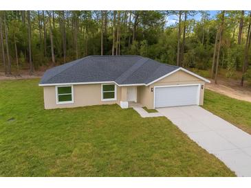 New home with a beige exterior, black roof, an attached garage, and a green lawn at 1050 Sw Obee Ridge Rd, Dunnellon, FL 34431