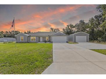 Charming single-story home features a well-maintained lawn, large driveway and detached two-car garage at 4661 Sw Gardenia Ct, Dunnellon, FL 34431