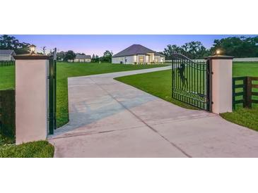Elegant gated entrance with long drive leading to a well-manicured lawn and stunning modern farmhouse at 7041 Ne 22Nd Court Rd, Ocala, FL 34479