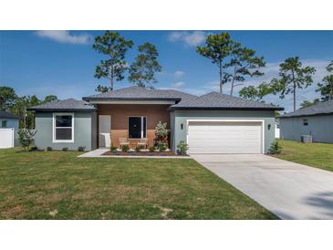 Charming single-story home with a manicured lawn, two-car garage, and inviting front entrance at 7364 Sw 133 Ne Loop, Ocala, FL 34473