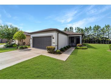 Charming single-story home featuring a well-manicured lawn, gray garage door, and inviting front entrance at 7707 Sw 94Th Cir, Ocala, FL 34481