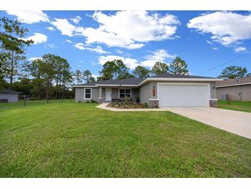 Charming single Gathering home featuring a well-manicured lawn, attached two-car garage, and welcoming front porch at 13479 Sw 100Th Ln, Dunnellon, FL 34432