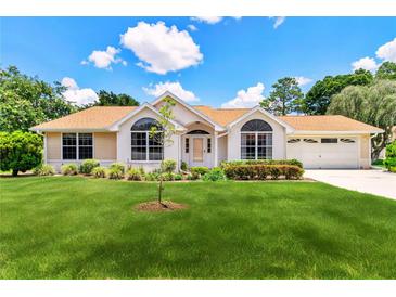 Charming single-story home with a manicured lawn, lush landscaping, and a welcoming entrance at 10819 Sw 84Th Ter, Ocala, FL 34481