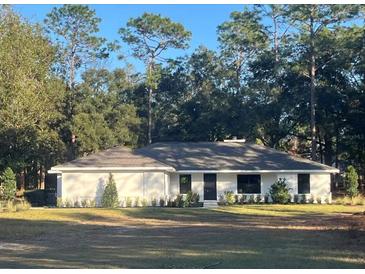 Charming single-story home featuring a neutral palette, well-maintained lawn, and lush surrounding trees at 1245 Nw 73Rd Ter, Ocala, FL 34482