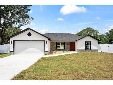 Charming single-story home featuring a two-car garage, landscaped front yard, and neutral color palette at 36 Pine Radl, Ocala, FL 34472