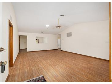 Spacious living room with wood-look floors, neutral walls and ceiling fan at 8959 Sw 96Th Ln # A, Ocala, FL 34481