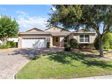 Charming single-story home with a well-manicured lawn and a brick driveway leading to a two-car garage at 9926 Sw 95Th Loop, Ocala, FL 34481