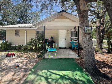 Quaint single-story home featuring a covered porch, natural landscaping, and mature shade trees at 15536 Se 203Rd Ave, Umatilla, FL 32784