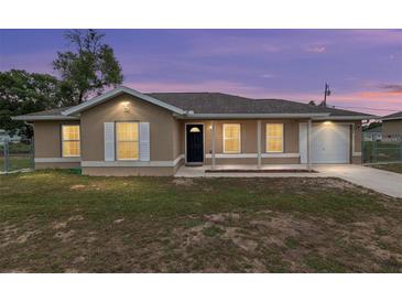 Charming single-story home featuring a covered porch, manicured lawn, and neutral exterior paint under a twilight sky at 2690 Sw 154Th Ln, Ocala, FL 34473