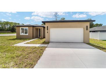 Charming single-story home with a large white garage door and nicely paved driveway at 5 Dogwood Loop Ave, Ocala, FL 34472