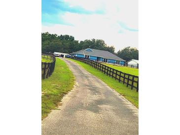 A long driveway leads to a single-story home with a black fenced in yard at 12524 Sw 109Th Pl, Dunnellon, FL 34432