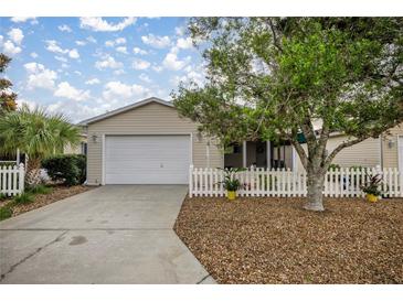 Charming one-story home featuring an attached garage, well-manicured landscaping, and a classic white picket fence at 1405 Espinoza Ln, The Villages, FL 32159