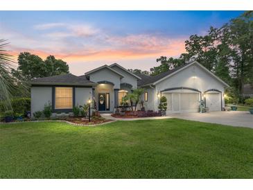 Charming one-story home with a well-manicured lawn and a three car garage, illuminated by twilight at 19115 Sw 98Th Loop, Dunnellon, FL 34432