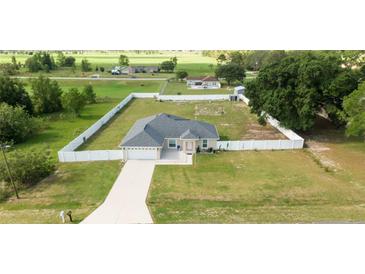 Expansive fenced property featuring a well-maintained lawn and a charming single-story home with an attached two-car garage at 6250 Se 88Th St, Ocala, FL 34472