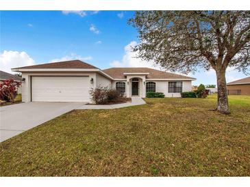 Single-story house with attached garage, and a well-maintained lawn at 1518 Blue Sky Blvd, Haines City, FL 33844