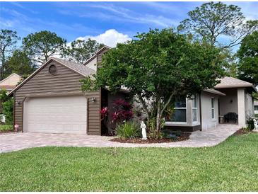 Charming single-story home with manicured lawn, brick driveway, mature tree, and two-car garage at 416 Sandestin Dr, Winter Haven, FL 33884