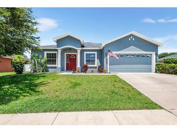 Charming single-story home with well-maintained lawn, classic columns, and a bright red front door at 192 Viola Dr, Auburndale, FL 33823