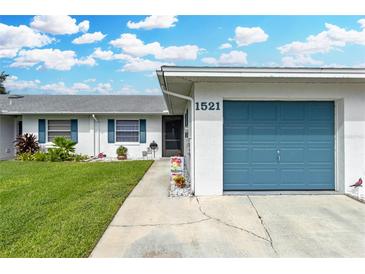 Front view of a single story home with a blue garage door and landscaped lawn at 1521 Oakview Se Cir, Winter Haven, FL 33880