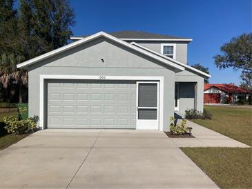 Two-story house with gray siding, a double-car garage, and a well-maintained lawn at 1300 Lucerne Loop Ne Rd, Winter Haven, FL 33881