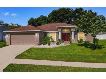 House exterior view with a brown roof, red door, and landscaped lawn at 5643 Fischer Dr, Lakeland, FL 33812