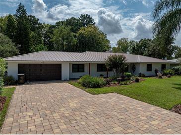 Charming one-story home featuring lush landscaping and a brick paver driveway at 3808 Gaines Dr, Winter Haven, FL 33884