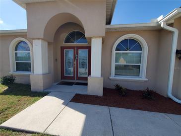Inviting front entrance with beautiful double doors, arched windows, and manicured landscaping at 2712 Oak Hammock Loop, Mulberry, FL 33860