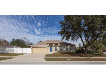 Tan house with blue door, garage and a large tree in front at 3696 Wellington Pl, Bartow, FL 33830