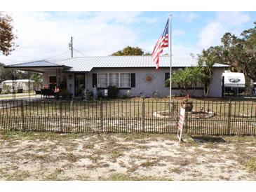 Charming single-story home with a metal roof, covered porch, fenced yard, and American flag waving out front at 5031 Timberlane Rd, Lake Wales, FL 33898