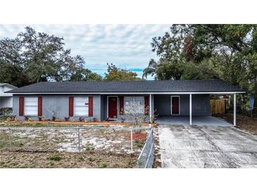 Newly renovated gray brick house with red accents, carport, and fenced yard at 115 7Th Jpv St, Winter Haven, FL 33880