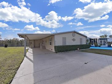 Tan mobile home with carport, landscaping, and paved driveway at 1750 Fox Hill Dr, Lakeland, FL 33810