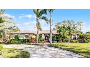 Beautiful single-story home with a well-maintained lawn, lush landscaping, and a circular driveway at 2428 Wildwood Ct, Winter Haven, FL 33884
