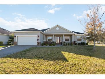 One-story home with gray siding, landscaped yard, and a paved driveway at 4462 Micanope Crescent Dr, Lakeland, FL 33811