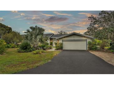 House exterior features a light-colored exterior, attached garage, and mature landscaping at 48 Nottingham Way, Haines City, FL 33844