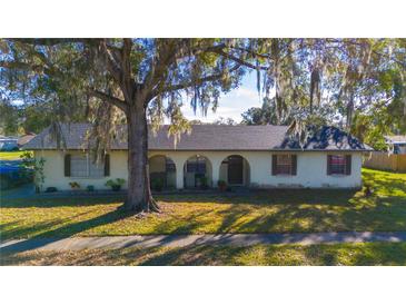 Single-story home with a large tree and manicured lawn at 5090 Misty Lake Dr, Mulberry, FL 33860