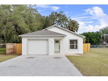 Newly constructed home with a white exterior, attached garage, and landscaped yard at 735 Avenue R Ne, Winter Haven, FL 33881