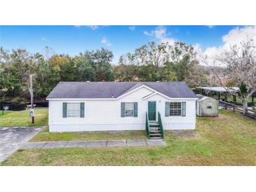 White single-wide manufactured home with green accents and a spacious yard at 13901 Hatchineha Rd, Haines City, FL 33844