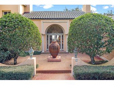 Elegant home entry with arched doorway, brick pavers, and lush landscaping at 2300 N Scenic Hwy # 37, Lake Wales, FL 33853