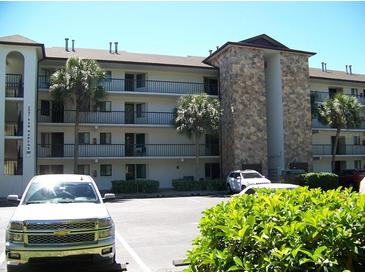 Multi-level condo building showcasing tropical landscaping and ample parking spaces for residents and guests at 333 Lake Howard Nw Dr # 202-A, Winter Haven, FL 33880