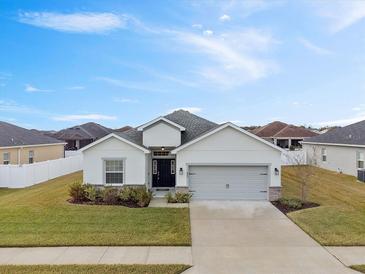 Single-story home with gray garage door and landscaping at 425 Riders Loop, Auburndale, FL 33823