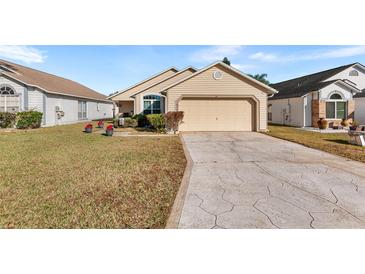 Tan one-story house with a two-car garage and well-maintained lawn at 426 Allison Ave, Davenport, FL 33897