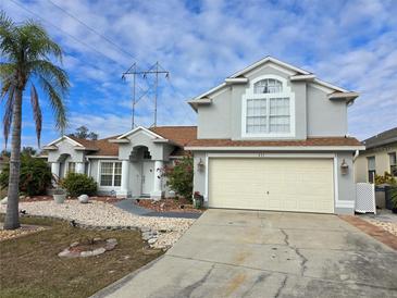 Two-story house with a beige exterior, landscaping, and a two-car garage at 437 Grand Reserve Dr, Davenport, FL 33837