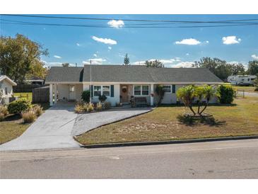 Tan house with green roof, landscaping, and driveway at 615 E Haines Blvd, Lake Alfred, FL 33850