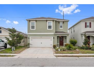 Two-story house with green exterior, white garage door, and landscaping at 723 Chinoy Rd, Davenport, FL 33837