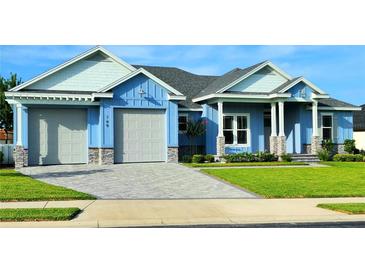Beautiful two-story home with light blue exterior, gray stone accents, and a large driveway at 780 Waterfern Trail Dr, Auburndale, FL 33823