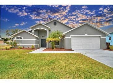 Gray house with two-car garage, palm trees, and well-maintained lawn at 1932 Southern Dunes Blvd, Haines City, FL 33844