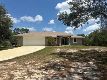 Charming single-story home featuring a two-car garage, neutral paint, and a well-manicured lawn at 2772 Indian Pipes Trl, Frostproof, FL 33843