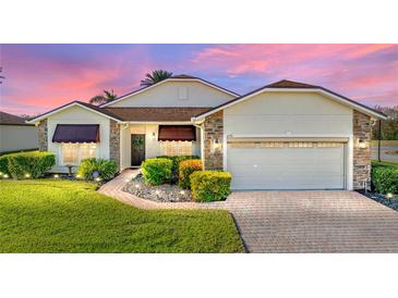 Attractive single-story home with landscaped yard, paver driveway, and two-car garage at 4195 Muirfield Loop, Lake Wales, FL 33859